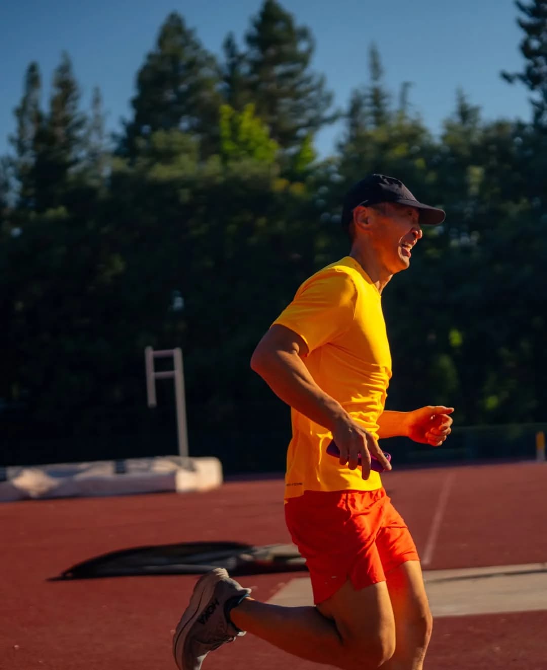 Tim running on a track in a yellow shirt and orange shorts